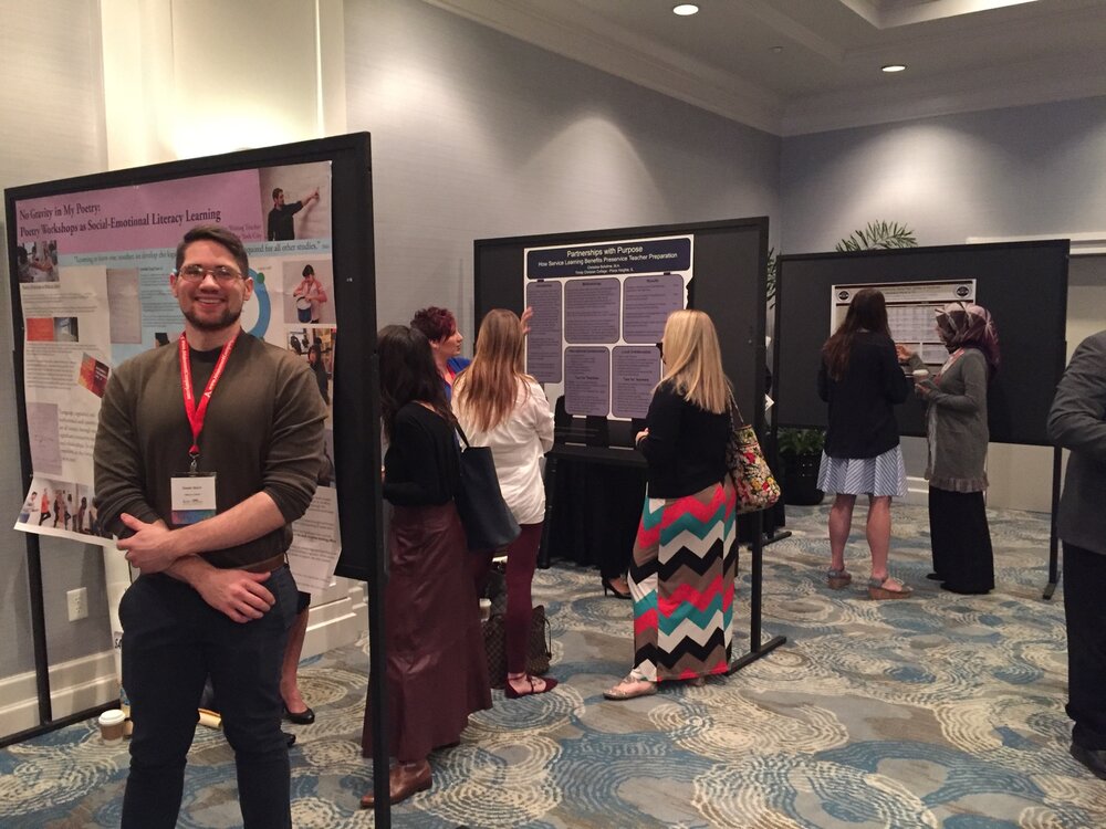 Donnie Welch, a young man in professional attire, stands in a hotel meeting room in front of an academic poster. In the background can be seen other posters and attendees in similar professional attire.